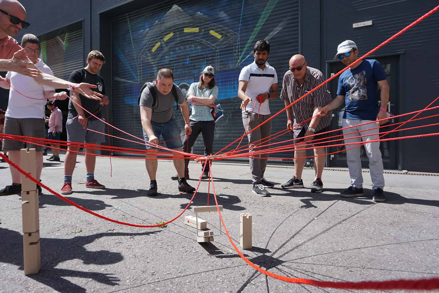 a group of people pulling a red rope teambuilding activity
