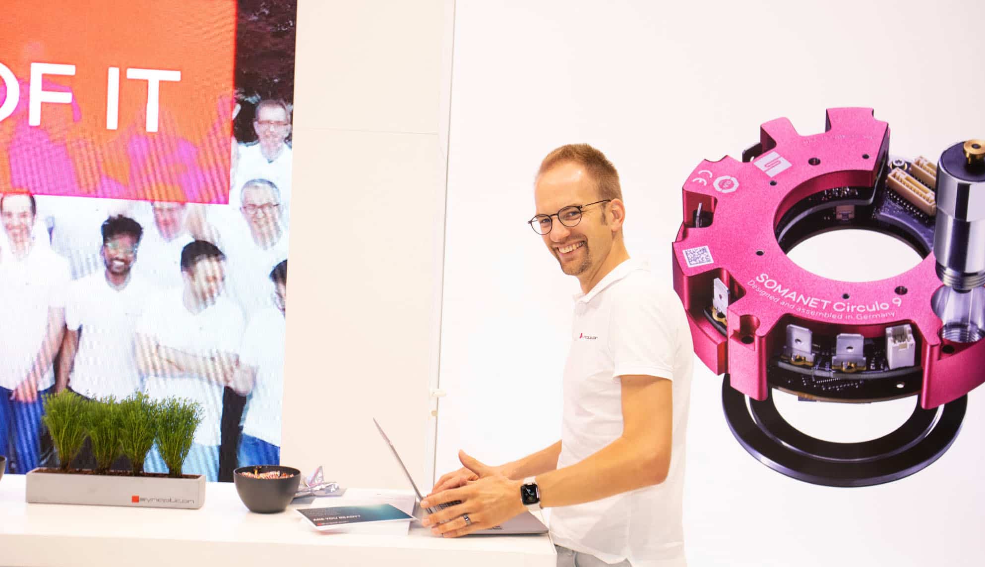a man standing in front of a desk with a laptop