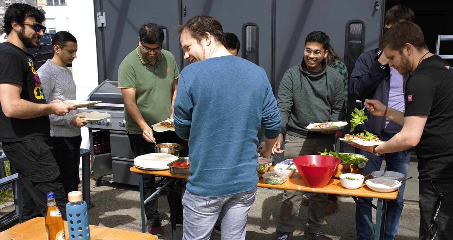 a group of men standing around a table with food on it