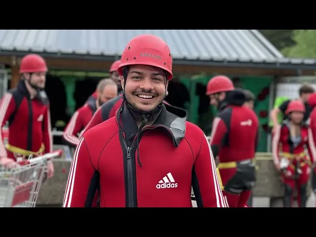 a man in a red jacket and helmet standing in front of a group of people