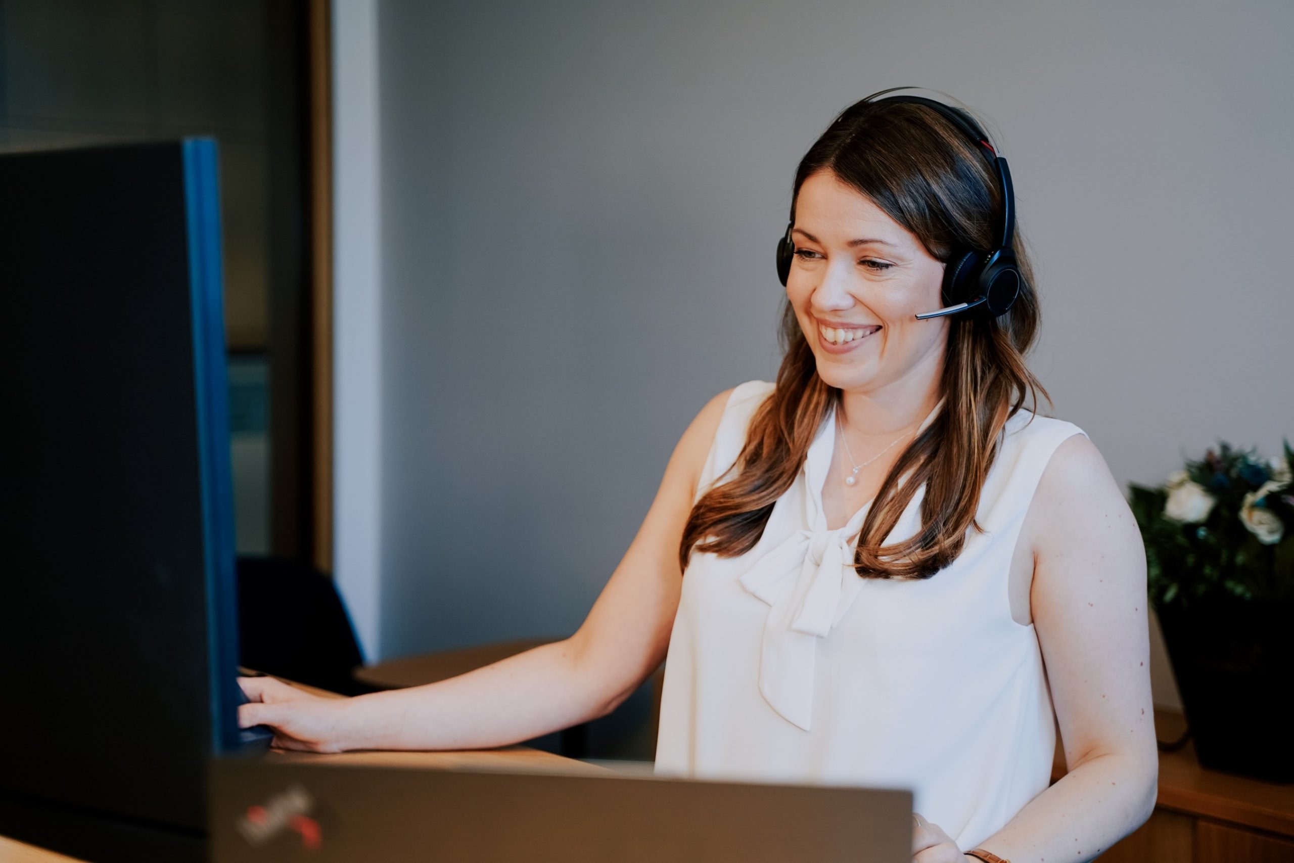 Mitarbeiterin im Business Support von WFW mit Headset im Gespräch