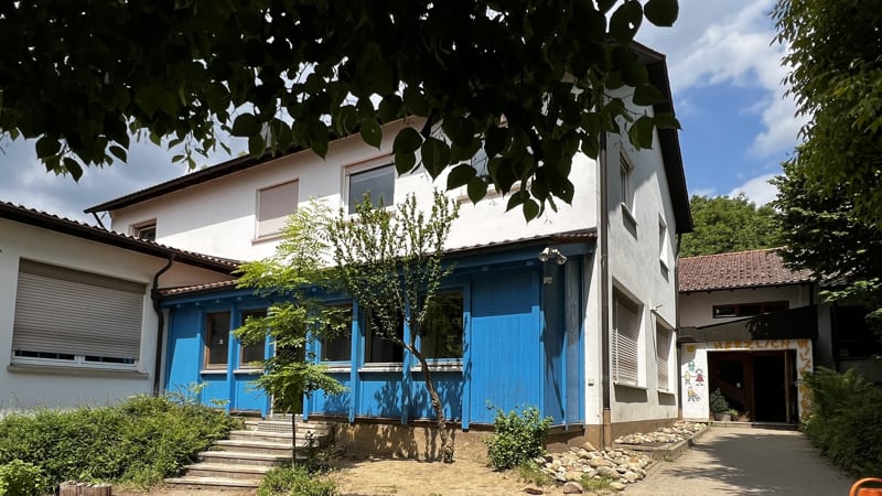 Außenansicht einer Kita mit blauem Anbau