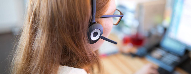 Mitarbeiterin mit Headset im Büro bei der Arbeit