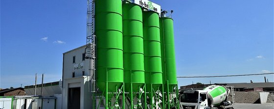 Betonmischanlage mit großen grünen Silos und Betonmischer-Fahrzeug