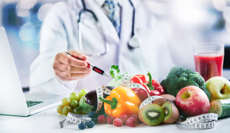 Arzt mit Obst, Gemüse und Maßband