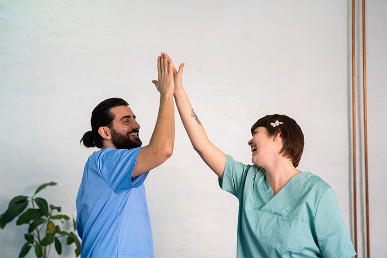 Mann und Frau in medizinischer Kleidung geben sich ein High Five