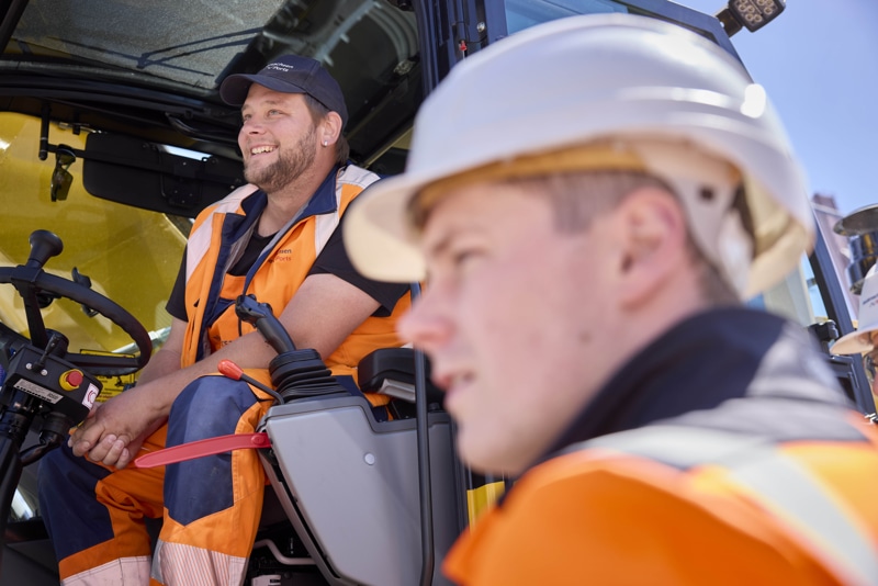 Ein Mann sitzt auf einem Traktor und ein junge Mann