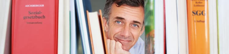 Mann zwischen Fachbüchern lächelt