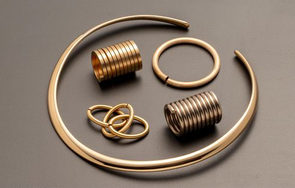 Dr. Bernhard Burger AG – Metallische Spiralfedern und Ringe auf grauem Hintergrund