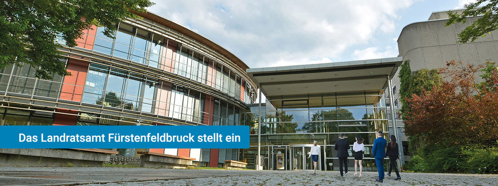 Außenaufnahme des Landratsamts Fürstenfeldbruck mit moderner Architektur und Personen im Eingangsbereich