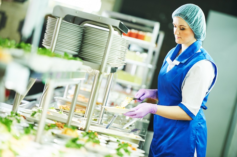 Kantinenmitarbeiterin serviert Essen
