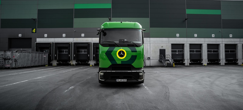 Grüner LKW vor einer Lagerhalle