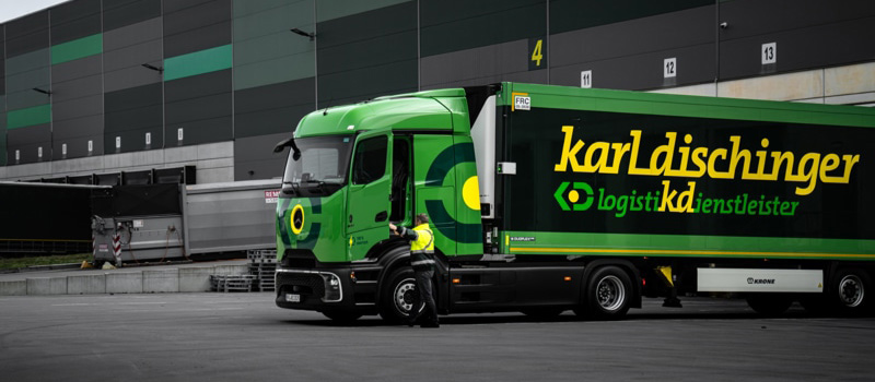 Grüner LKW vor einer Lagerhalle