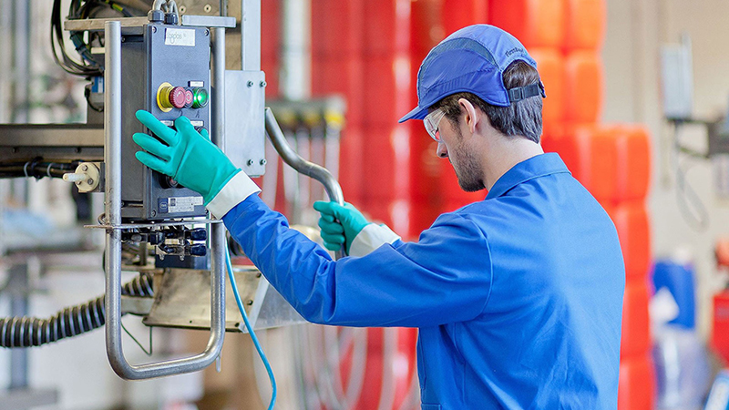 Arbeiter bedient Maschine mit Steuerelementen