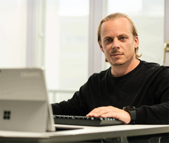 IT-Consultant arbeitet konzentriert am Laptop an einem modernen Arbeitsplatz