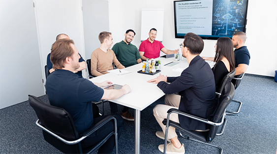 Team bei Besprechung in Konferenzraum mit digitalen Displays