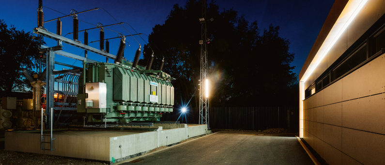 Hochspannungs-Transformatorenstation bei Nacht mit beleuchteter Infrastruktur