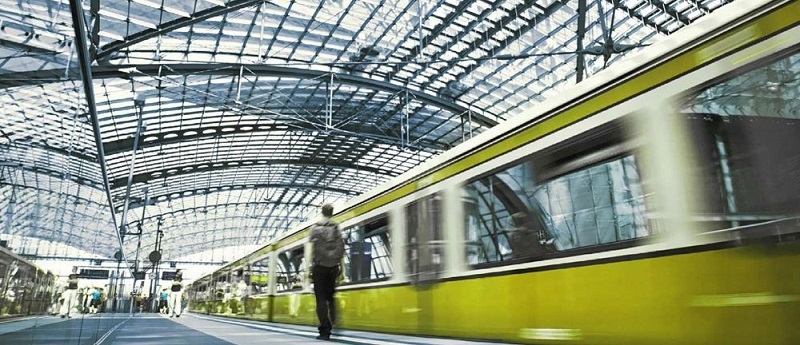 Bahnsteig mit modernem grünem Zug unter Glasdachkonstruktion