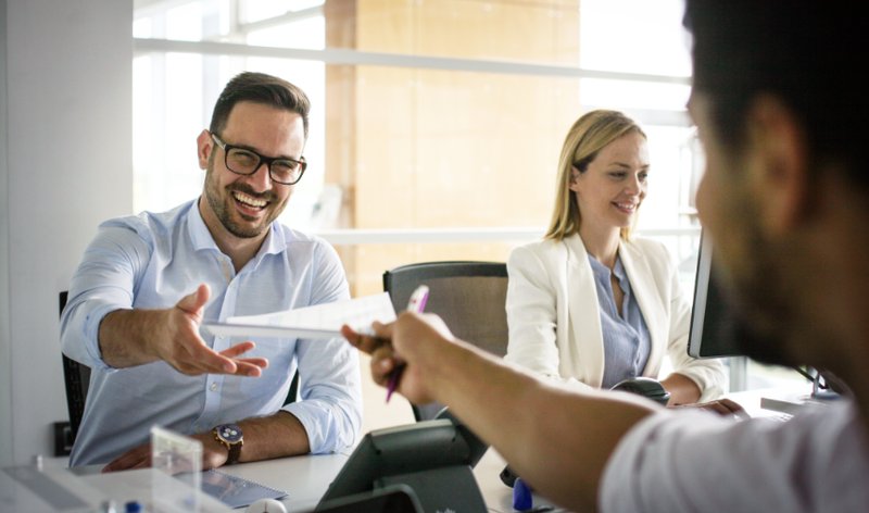Drei Personen in einem Büro führen ein Gespräch am Konferenztisch