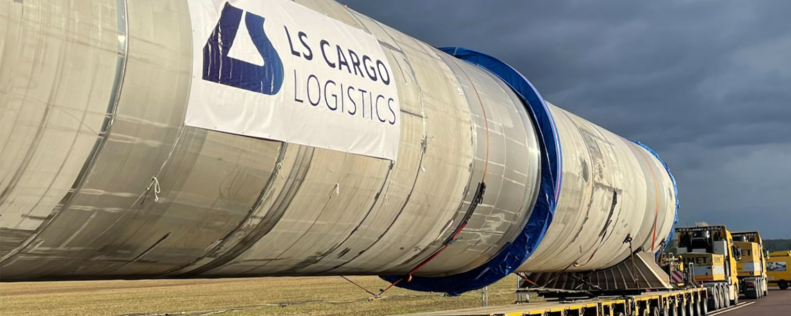 Schwertransport eines großen Anlagenteils mit LS-Cargo-Logistics-Banner auf einem Tieflader