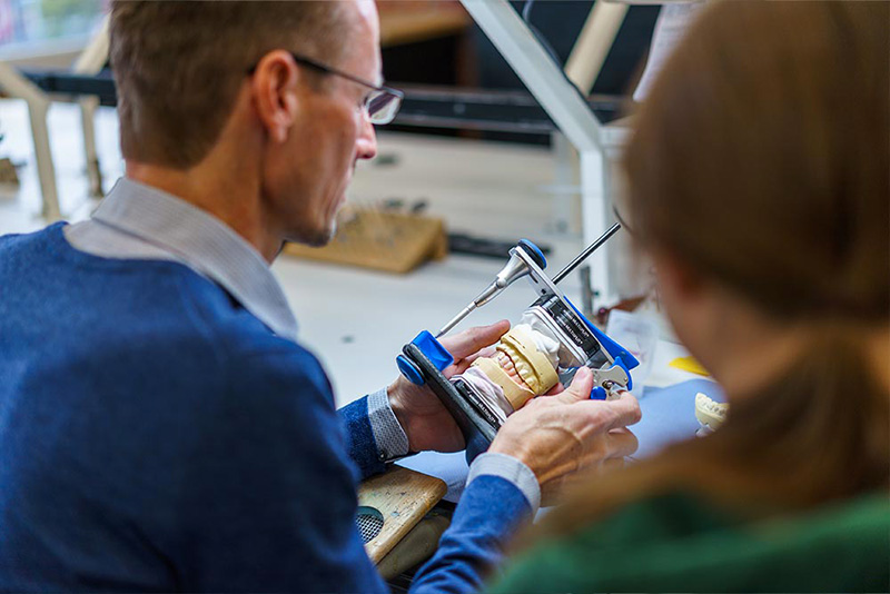 Zahntechniker prüft ein Modell im Artikulator