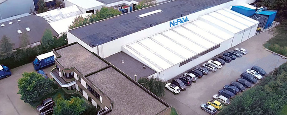 Luftaufnahme des Firmengebäudes der NOREVA mit Parkplatz und blauem Firmenlogo auf dem Hallendach