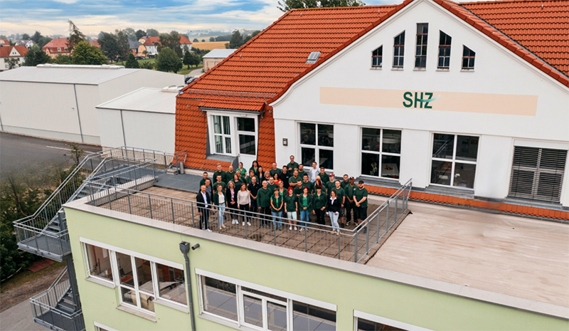 Gruppenfoto des SHZ-Teams auf einer Dachterrasse vor dem Firmengebäude