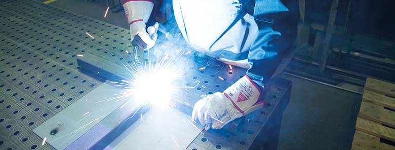 Person schweißt Metall an einem Werktisch