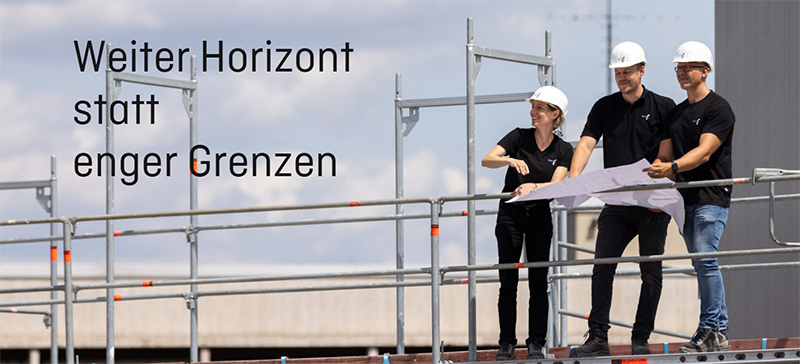 Drei Personen mit Bauplänen auf einem Gerüst - Weiter Horizont statt enger Grenzen