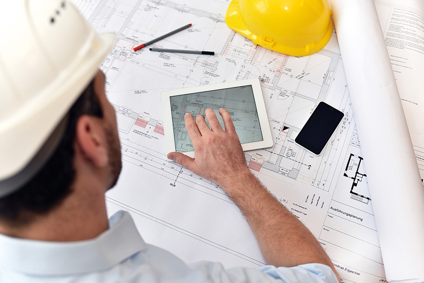 Bauleiter prüft Bauplan mit Tablet