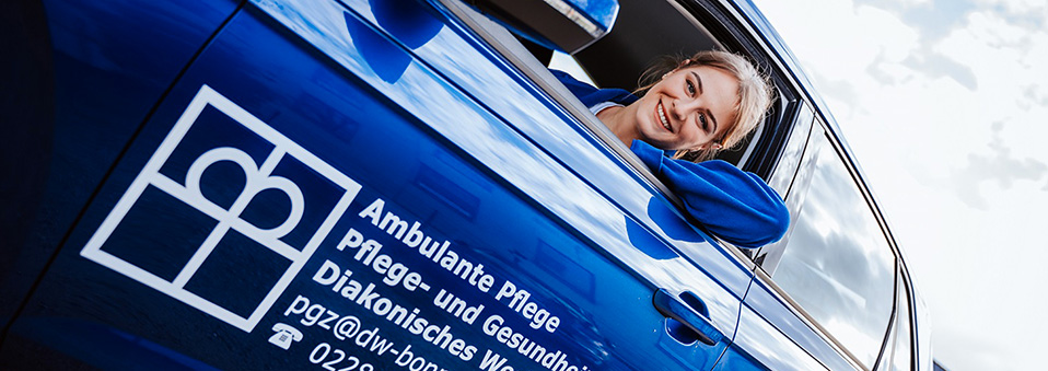 Pflegekraft im Dienstfahrzeug lächelnd