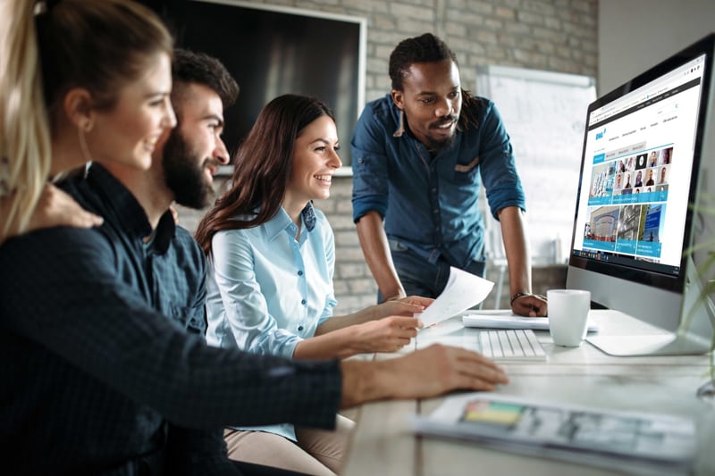 Ein vierköpfiges Team arbeitet gemeinsam an einem Computer