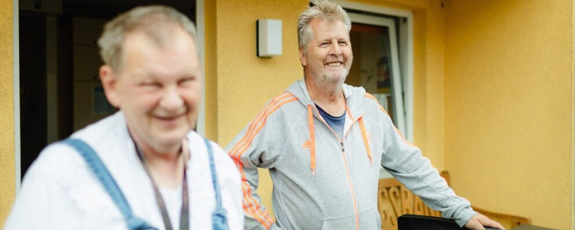 header_zwei_maenner_vor_gelben_haus.jpg