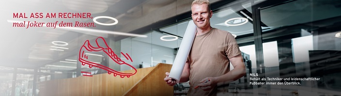 Mitarbeiter Nils hält eine Planrolle und lächelt in die Kamera