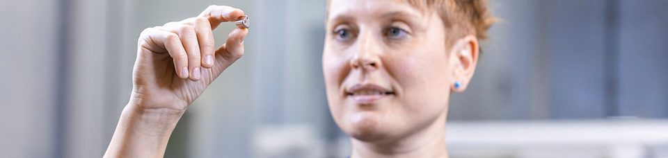 Frau betrachtet winziges Bauteil