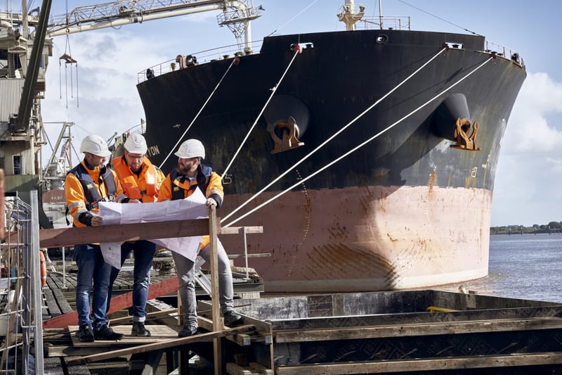 Drei Planer vor großem Frachtschiff
